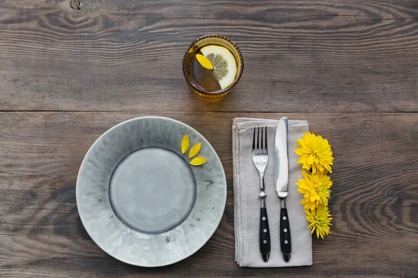Rustik tablo ayarını keten peçete, çatal bıçak takımları, seramik kaplamalar, sarı gözlük ve sarı çiçek