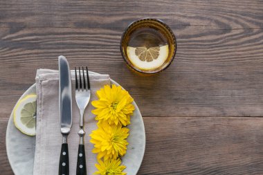 Rustik sofra keten peçete, çatal bıçak takımları, seramik kaplamalar, sarı gözlük ve koyu ahşap masaya sarı çiçek. Tatil masa dekorasyonu. Romantik bir akşam yemeği.