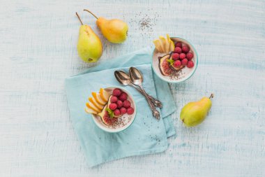 Taze meyve, chia tohum, ahududu ve sağlıklı vegan vejetaryen diyet kahvaltı için beyaz rustik ahşap arka plan üzerinde incir ile güler yüzlü kase. Sağlıklı gıda kavramı. Üstten görünüm