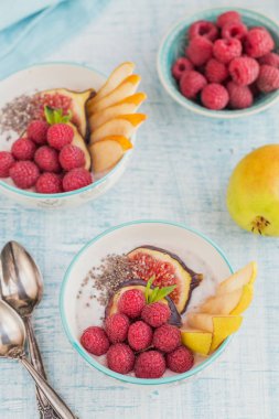 Taze meyve, chia tohum, ahududu ve sağlıklı vegan vejetaryen diyet kahvaltı için beyaz rustik ahşap arka plan üzerinde incir ile güler yüzlü kase. Sağlıklı gıda kavramı. Ek yük