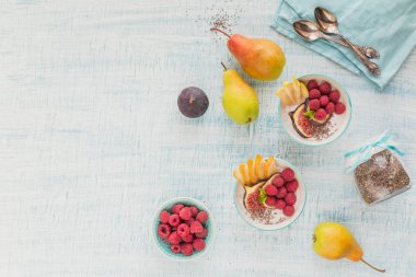 Taze meyve, chia tohum, ahududu ve sağlıklı vegan vejetaryen diyet kahvaltı için beyaz rustik ahşap arka plan üzerinde incir ile güler yüzlü kase. Sağlıklı gıda kavramı. Üstten görünüm