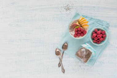 Taze meyve, chia tohum, ahududu ve sağlıklı vegan vejetaryen diyet kahvaltı için beyaz rustik ahşap arka plan üzerinde incir ile güler yüzlü kase. Sağlıklı gıda kavramı. Yukarıdaki metin kopyalama yeri olan