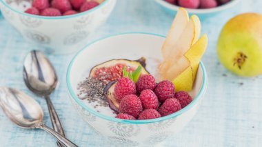 Taze meyve, chia tohum, ahududu ve sağlıklı vegan vejetaryen diyet kahvaltı için beyaz rustik ahşap arka plan üzerinde incir ile güler yüzlü kase. Sağlıklı gıda kavramı. Yakın çekim