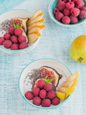Taze meyve, chia tohum, ahududu ve sağlıklı vegan vejetaryen diyet kahvaltı için beyaz rustik ahşap arka plan üzerinde incir ile güler yüzlü kase. Sağlıklı gıda kavramı. Üstten görünüm
