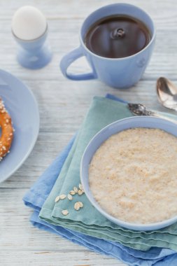 Siyah çay ve beyaz ahşap zemin üzerine haşlanmış yumurta ile yulaf lapası kase. Sağlıklı besleyici kahvaltı. Kavramı, sağlıklı beslenme, diyet. 