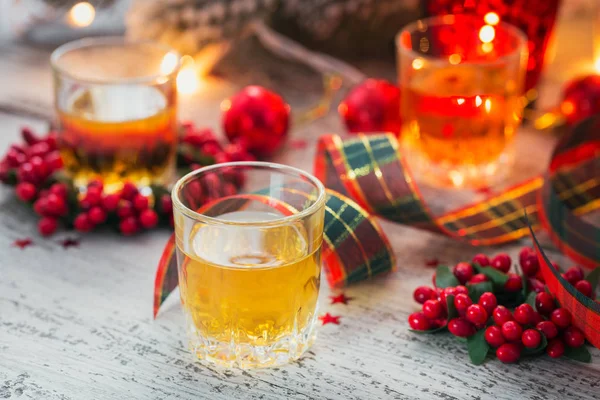 Viski, konyak ya da likör atış ve Noel süslemeleri Beyaz ahşap zemin üzerinde. Kış tatil kavramı.