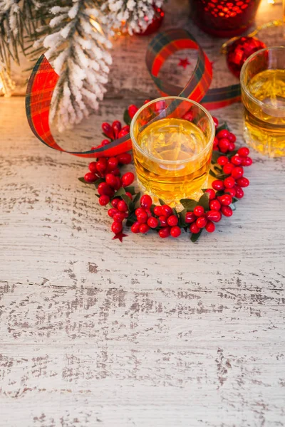 Whiskey, brandy or liquor shot and Christmas decorations on white wooden background. Winter holidays concept.