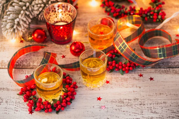 Whiskey, brandy or liquor shot and Christmas decorations on white wooden background. Christmas holidays concept.