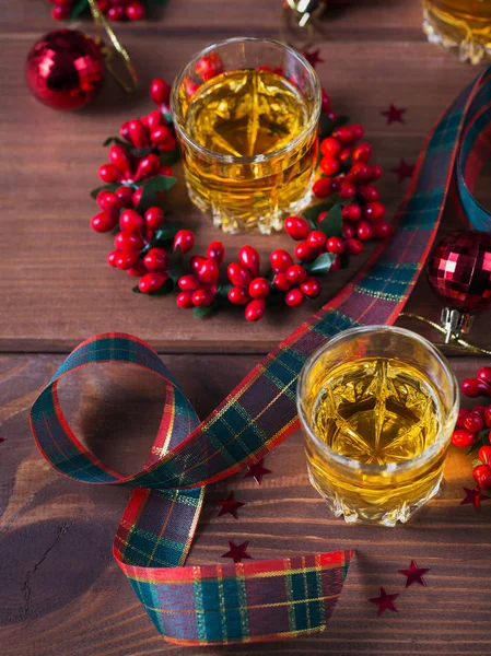 Whiskey, brandy or liquor shot and Christmas decorations on wooden background. Winter holidays concept. Top view