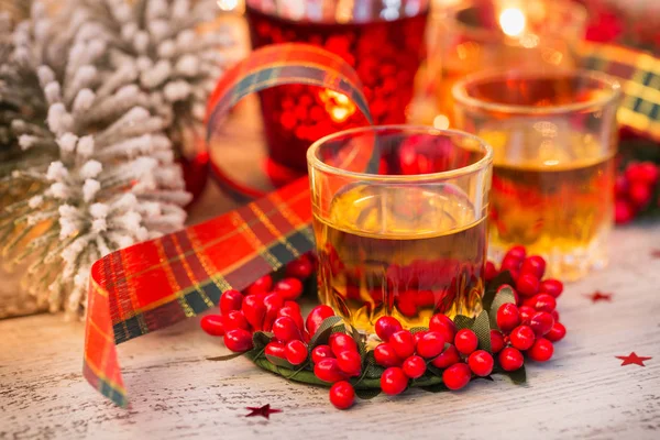 Whiskey, brandy or liquor shot and Christmas decorations on white wooden background. Winter holidays concept. Close up