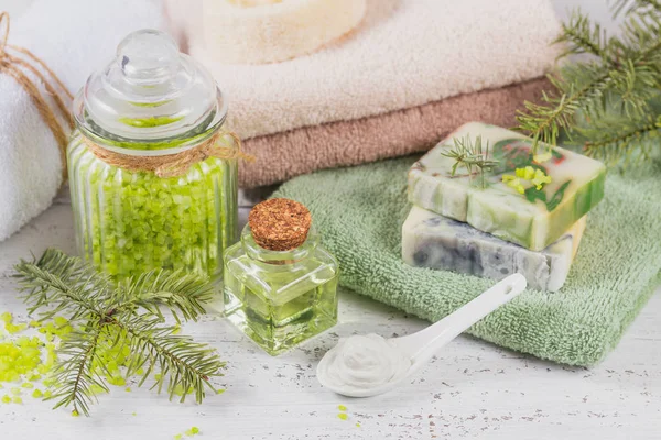 Natural cosmetic oil, sea salt, facial mask and natural handmade soap with coniferous extract on white rustic wooden background. Healthy skin, facial and body care. SPA and sauna concept.