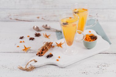 İki yüksek gözlük ile renkli sıcak deniz cehri çay tarçın, Anason yıldız ve taze deniz cehri çilek Beyaz ahşap rustik masa üzerinde.