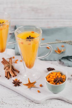 İki yüksek gözlük ile renkli sıcak deniz cehri çay tarçın, Anason yıldız ve taze deniz cehri çilek Beyaz ahşap rustik masa üzerinde.