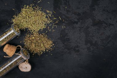 Siyah arka planda çeşitli baharatlar ve otlar. Yiyecek için baharatlar. Cam kaplarda biberiye ve fesleğen. Yemek pişirmek için ev yapımı baharatlar.