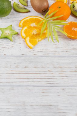 Yeşil palmiye yaprakları ve beyaz tahta masada meyvelerin taze tropikal dilimleri. Sulu portakal, mandalina, limon, kivi, carambolas. Yaz meyve arka plan. Düz yatıyordu, en iyi görünüm, kopya alanı