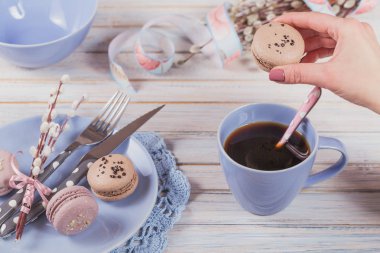 Paskalya sofra kahve, acıbadem kurabiyesi kurabiye, söğüt dalları ve çatal bıçak takımı ile. Kadın acıbadem kurabiyesi tutar. Bahar tatil kavramı