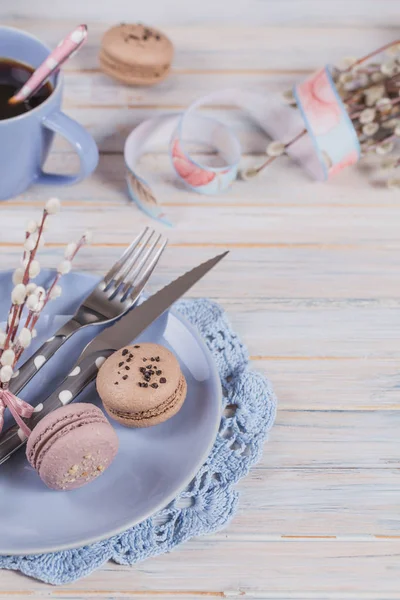 Easter table setting with coffee, macaroon cookies, willow branches and cutlery. Spring holiday concept