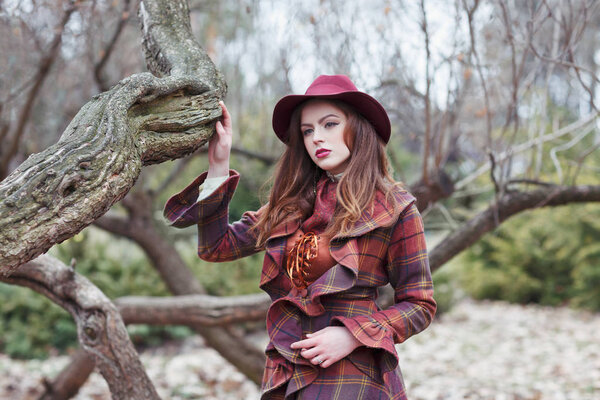 Beautiful woman in a vintage clothing and elegant hat in a misterious forest