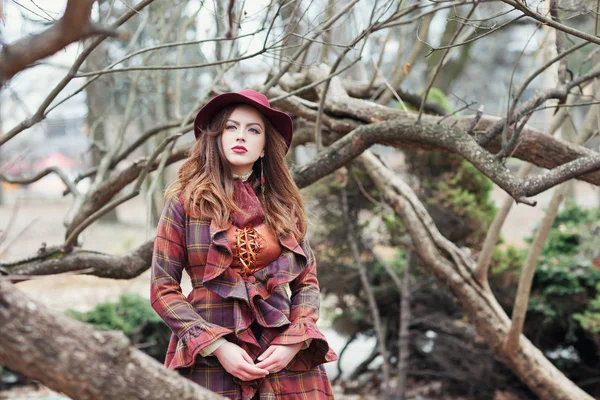 Beautiful woman in a vintage clothing and elegant hat in forest
