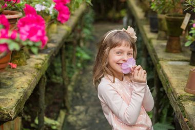 Sera çiçeklerle oynarken küçük kız.