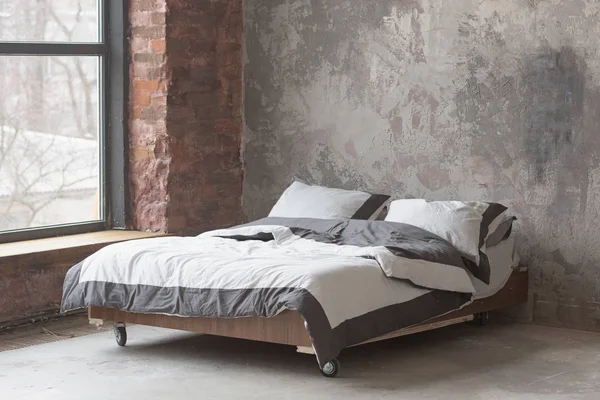 Loft style bedroom interior with bed, gray design, brick texture