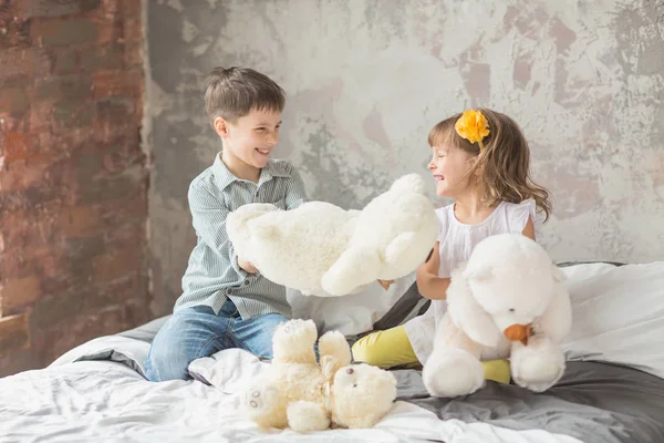 Hermano y hermana jugando con el oso de peluche en la cama — Foto de Stock