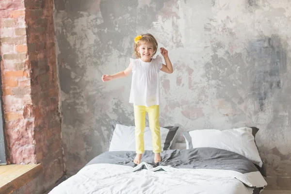 Feliz niña que se divierte saltando en una cama —  Fotos de Stock