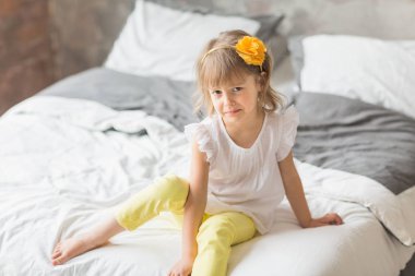 Sevimli küçük kız yatakta oturur ve ağlıyor