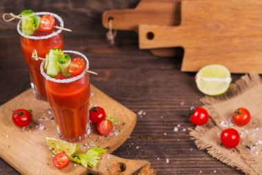 İki bardak domates suyu taze domates, cucum ile dekore edilmiştir.