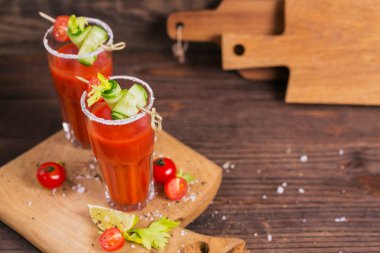 İki bardak domates suyu taze domates, cucum ile dekore edilmiştir.