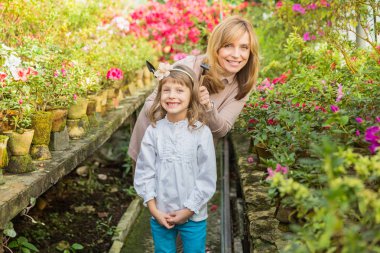 Anne ve kız carying bitkiler, serada Bahçe