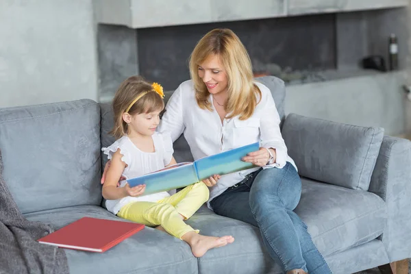 Madre e hija están jugando, leyendo un libro, sentadas — Foto de Stock