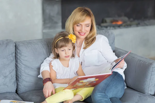 Madre e hija están jugando, leyendo un libro, sentadas — Foto de Stock
