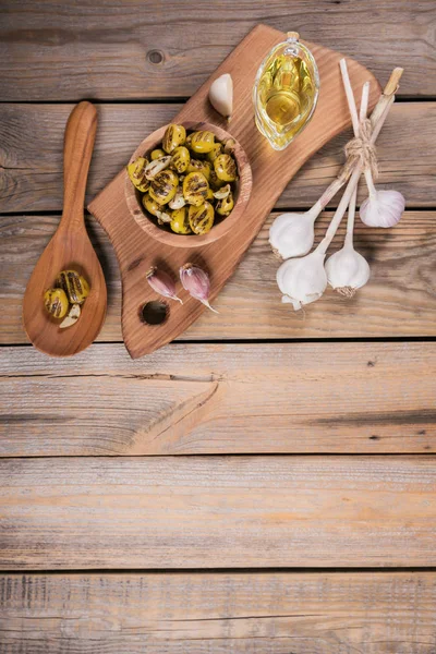 Aceitunas a la parrilla con ajo, aceite de oliva y especias en respaldo de madera — Foto de Stock