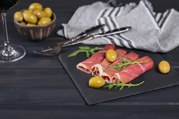 Black stone platter with slices of cured ham or Spanish jamon se