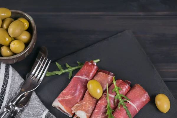 Black stone platter with slices of cured ham or Spanish jamon se