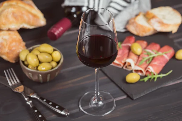 Verre de vin rouge avec des tranches de jambon salé ou de jamon serr espagnol — Photo