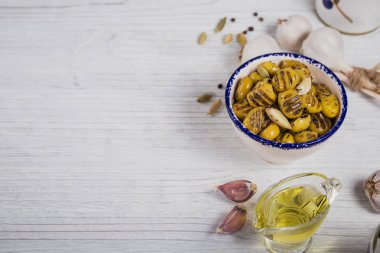 Beyaz rustik üzerinde sarımsak, zeytinyağı ve baharatlar ile ızgara zeytin