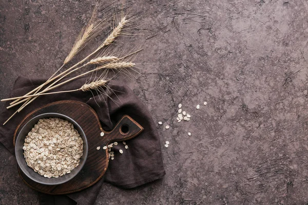 Миска з сухих вівсяних пластівців з вухами пшениці на темному фоні. Співзасновник — стокове фото
