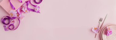 Açık arkaplanda çiçek ve masa ayarları. Seramik tabaklar, çatal bıçak takımı, mor kurdeleli pembe hediye çantası ve pembe orkide çiçekleri. Tatil modern masa dekorasyonu