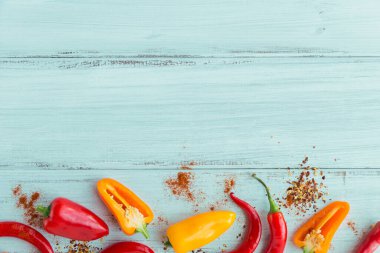 Açık mavi ahşap masada çeşitli baharatlar ve renkli biberlerin üst görüntüsü. Metin için serbest baharat içeren baharatlar