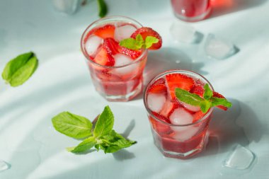 Beyaz köpüklü şaraplı yaz içkisi. Ev yapımı taze meyve kokteyli ya da şampanya, çilek, buz ve açık mavi arka planda biberiye ile punç..