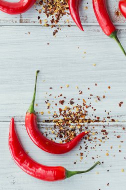 Çiğ organik kırmızı biber ve beyaz ahşap arka planda çeşitli baharatlar. Gıda çerçevesi için baharatlar.