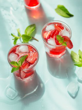 Açık mavi arka planda çilekli soda bardakları. Yaz sağlıklı detoks limonata, kokteyl ya da başka bir içki geçmişi. Alkolsüz içecekler, süper yiyecekler, vejetaryen ya da sağlıklı beslenme konsepti.