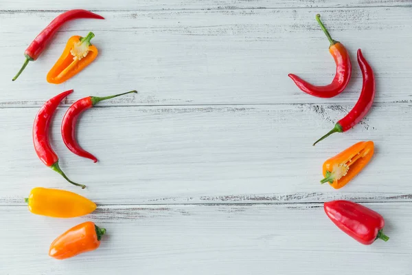 Top view of assorted colorful peppers on white wooden table. Seasonings background with free spice for text