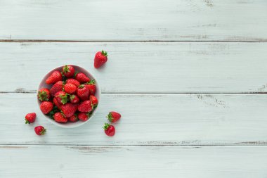 Seramik kasenin üstünde taze çilekler. Beyaz ahşap masa maketinde sağlıklı yiyecekler. Lezzetli, tatlı, sulu ve olgun arkaplanlı metin için kopya alanı