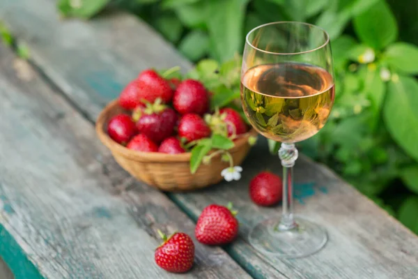 Ένα ποτήρι ροζέ κρασί σερβιρισμένο με φρέσκες φράουλες σε ξύλινο φόντο. Πικνίκ εξωτερική με ροζ κρασί και μούρα. — Φωτογραφία Αρχείου