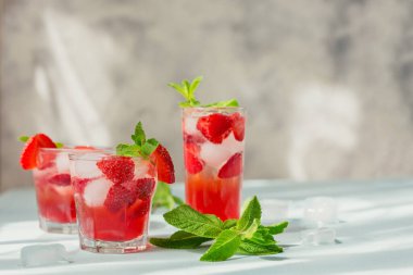 Taze çilek kokteyli. Açık mavi arka planda çilekli ve buzlu yaz pembe kokteyli. Metin için kopyalama alanı olan moda gölgeler ve güneş ışığı arkaplanı.