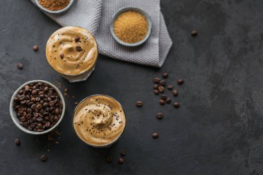 Dalgona kremalı kahve, hazır, kremalı, buzlu kahve. Siyah arka planda kahve, süt ve buz küplü kokteyl. Metin için kopyalama alanı olan modaya uygun içecek arkaplanı.