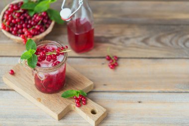 Cam kavanozda taze kuşüzümü kokteyli. Kırmızı frenk üzümü ve ahşap zemin üzerinde buz küpleri ile yaz pembe kokteyli metin için metin alanı ile taklit edilir.